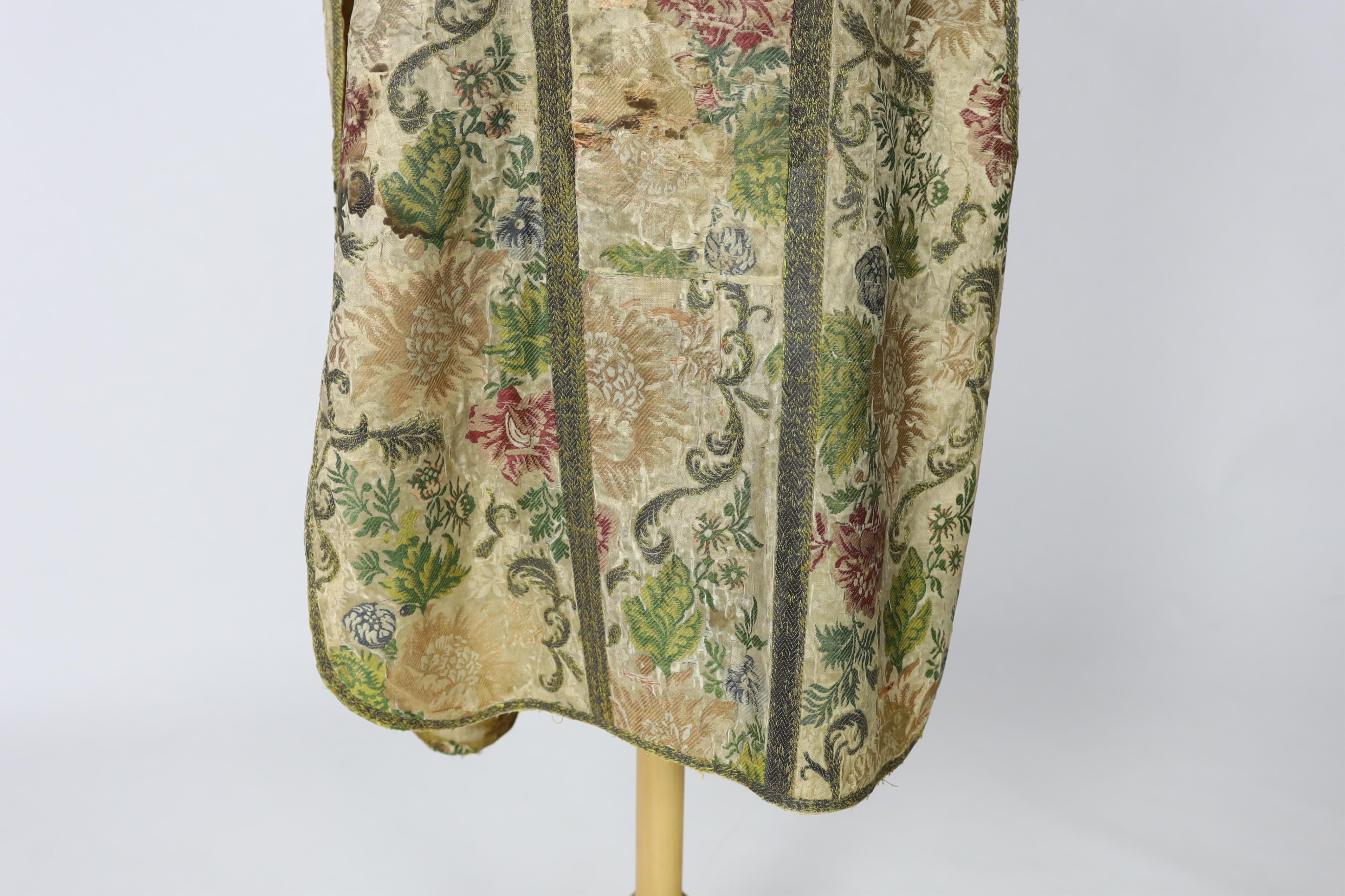 A late 18th century continental, possibly French, silk multi coloured and metallic brocade chasuble, lined with thick linen, edged and panelled with a thick metallic braid, 99cm long